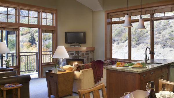 This image shows a cozy living and dining area with large windows, a couch, a television, and a dining table set for four.